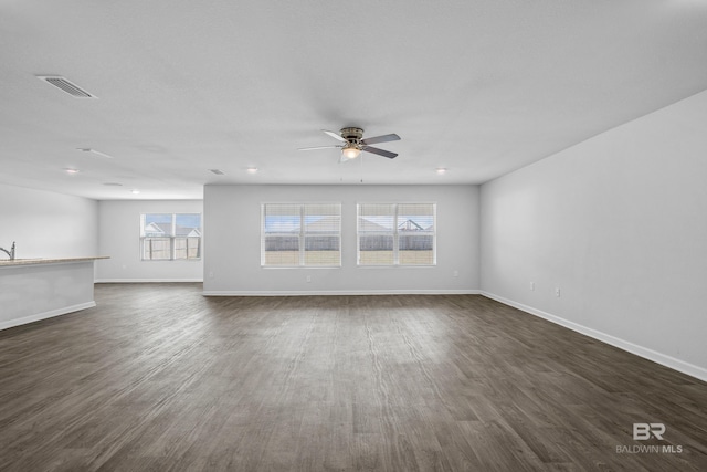 unfurnished living room featuring dark wood-type flooring and ceiling fan