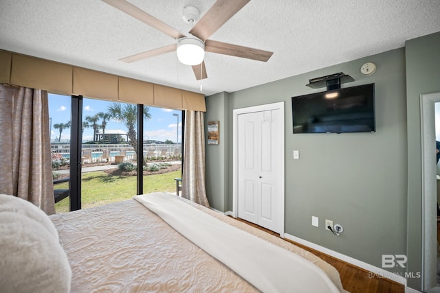 bedroom featuring access to exterior, baseboards, a closet, a textured ceiling, and a ceiling fan