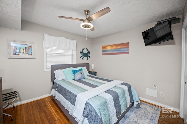 bedroom featuring a ceiling fan, wood finished floors, baseboards, and a textured ceiling