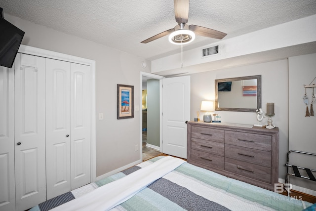 bedroom featuring visible vents, baseboards, a closet, a textured ceiling, and a ceiling fan