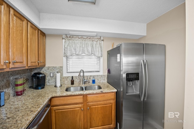 kitchen with a sink, light stone counters, brown cabinetry, and stainless steel appliances