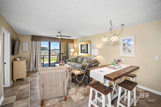 living room featuring baseboards, a textured ceiling, an inviting chandelier, and tile patterned flooring