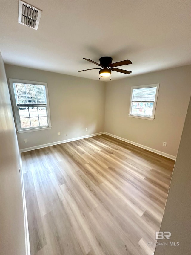 empty room with light hardwood / wood-style flooring, ceiling fan, and a healthy amount of sunlight