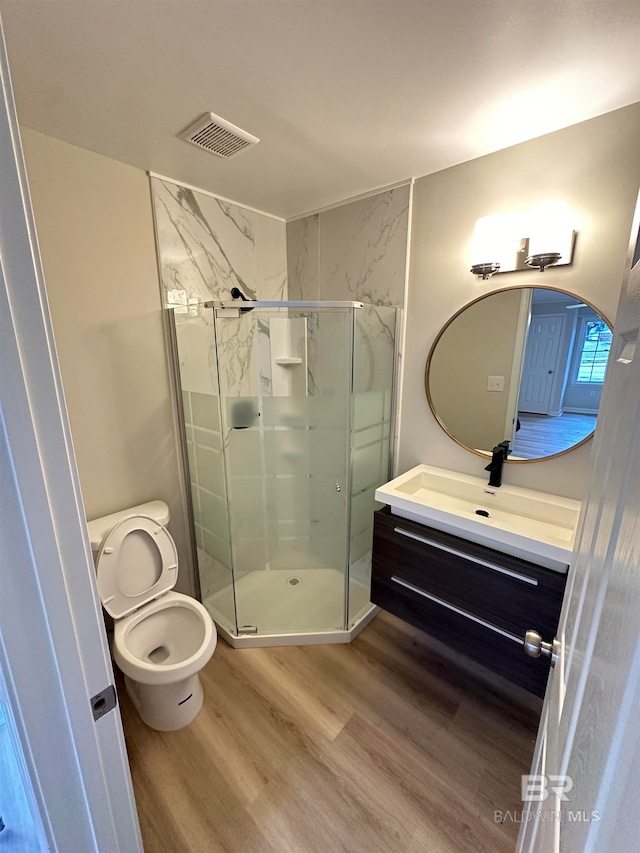 bathroom with vanity, hardwood / wood-style flooring, toilet, and a shower with door