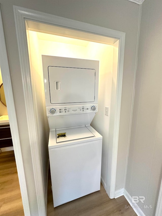 laundry area featuring wood-type flooring and stacked washer and clothes dryer