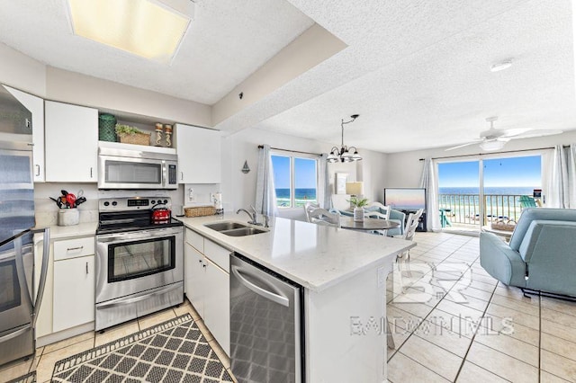 kitchen featuring kitchen peninsula, white cabinets, a textured ceiling, and appliances with stainless steel finishes