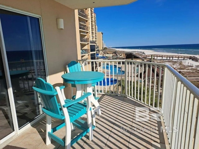 balcony featuring a view of the beach and a water view