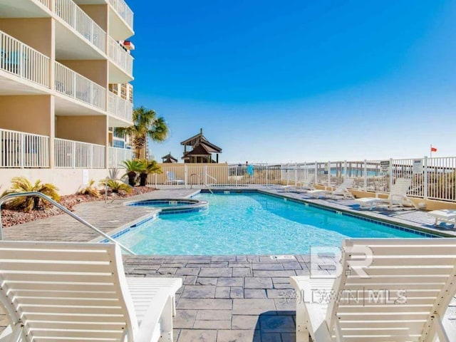 view of swimming pool featuring a patio and a hot tub