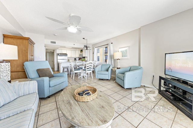 tiled living room featuring ceiling fan with notable chandelier and a textured ceiling