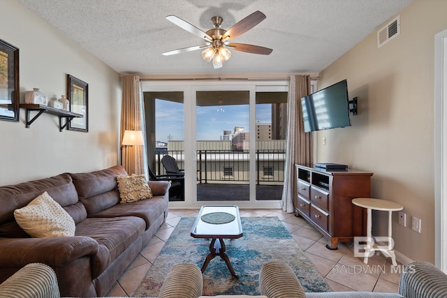 living room featuring light tile patterned flooring, ceiling fan, and a textured ceiling