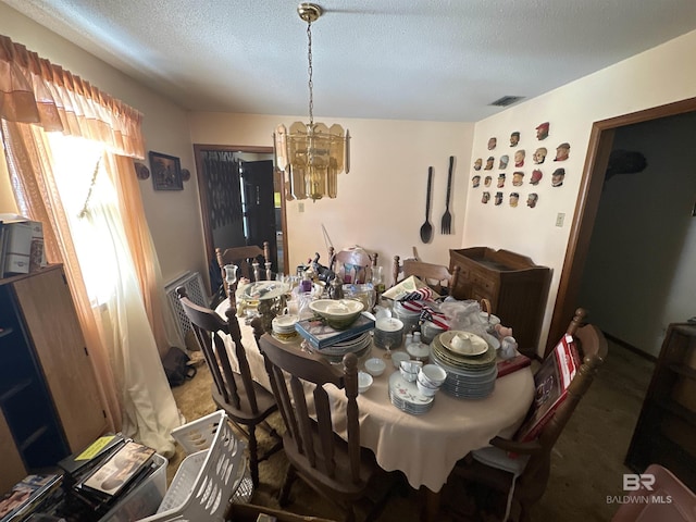 dining area with a notable chandelier, dark carpet, and a textured ceiling