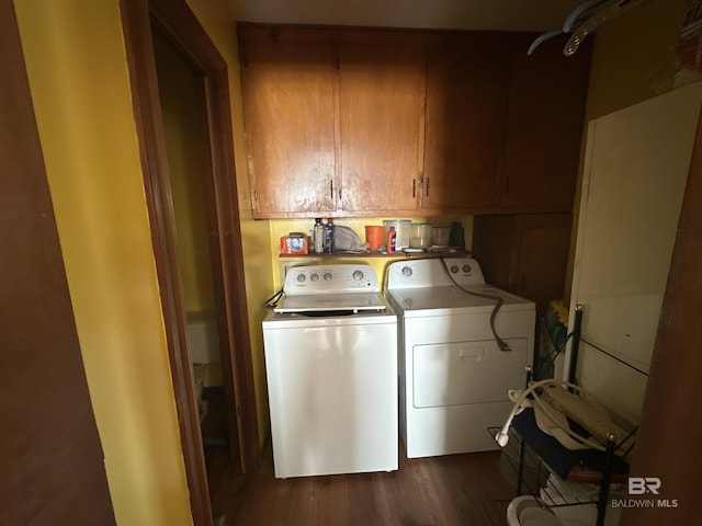 clothes washing area with washing machine and clothes dryer, cabinets, and dark hardwood / wood-style floors