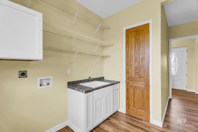 clothes washing area featuring hookup for a washing machine, light wood-style flooring, hookup for an electric dryer, a sink, and baseboards