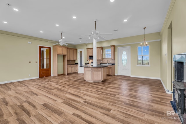 kitchen featuring light wood-style floors, a ceiling fan, dark countertops, open floor plan, and baseboards