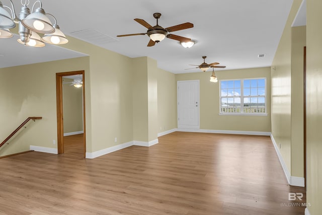 unfurnished living room featuring light wood-type flooring, ceiling fan with notable chandelier, baseboards, and visible vents