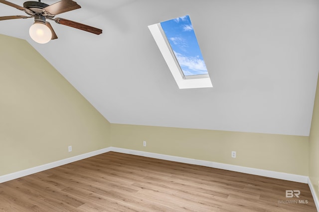 bonus room featuring vaulted ceiling with skylight, light wood finished floors, and baseboards