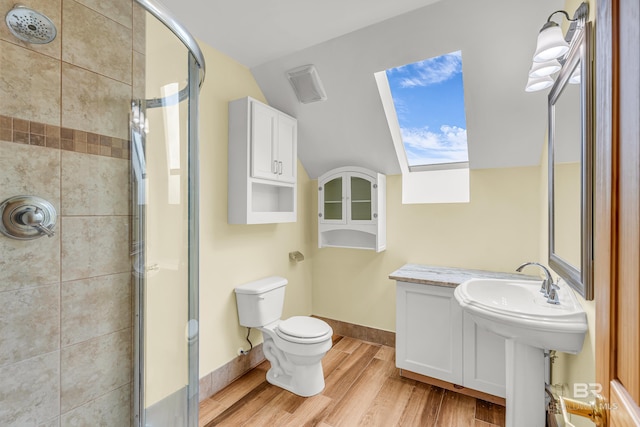 bathroom with visible vents, toilet, vaulted ceiling, wood finished floors, and a stall shower