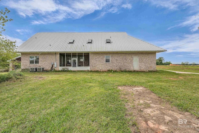 rear view of property with a sunroom, brick siding, metal roof, and a lawn