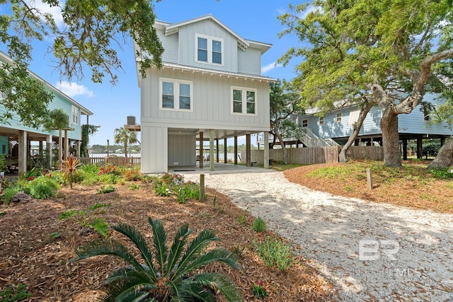 beach home featuring fence, a carport, board and batten siding, and driveway