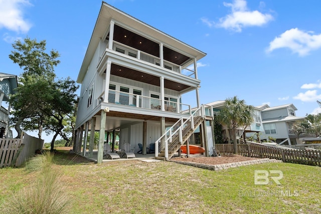 back of property featuring a balcony, a fenced backyard, board and batten siding, a lawn, and stairway