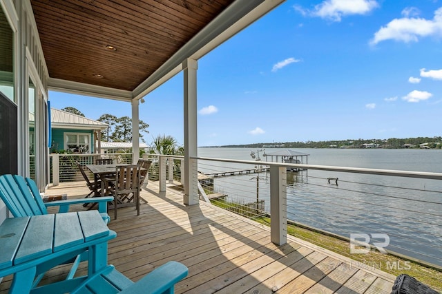 wooden deck with outdoor dining area and a water view