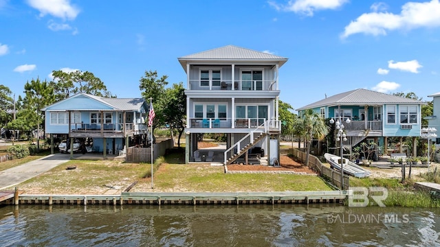 rear view of property with a water view, a carport, a balcony, and stairs