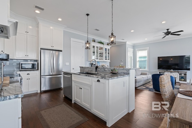 kitchen featuring visible vents, crown molding, a sink, open floor plan, and stainless steel appliances