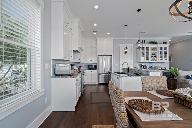 kitchen featuring appliances with stainless steel finishes, a wealth of natural light, a sink, and an island with sink
