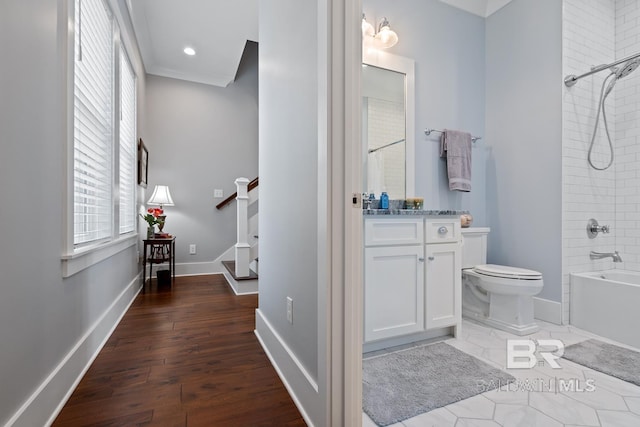 bathroom with vanity, wood finished floors, toilet, baseboards, and shower / tub combination