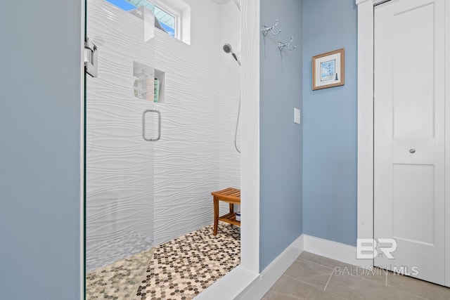 full bathroom with tiled shower and tile patterned flooring