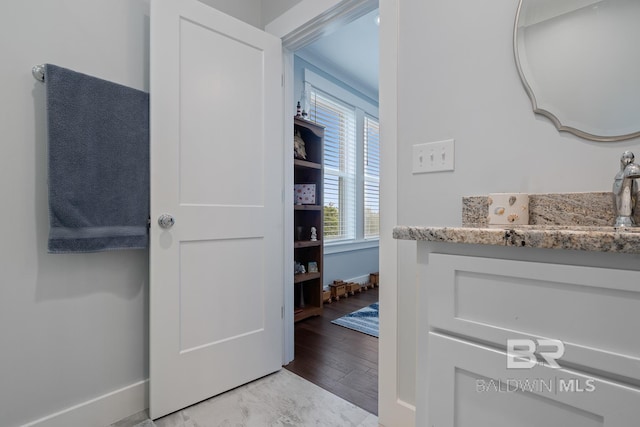 bathroom featuring baseboards, a sink, and wood finished floors