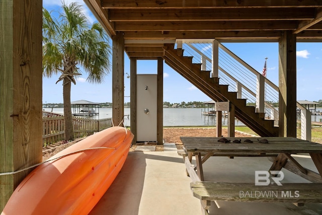 view of patio featuring fence, a water view, and stairway