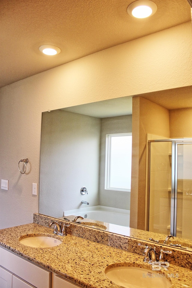 full bath with a sink, double vanity, and a stall shower