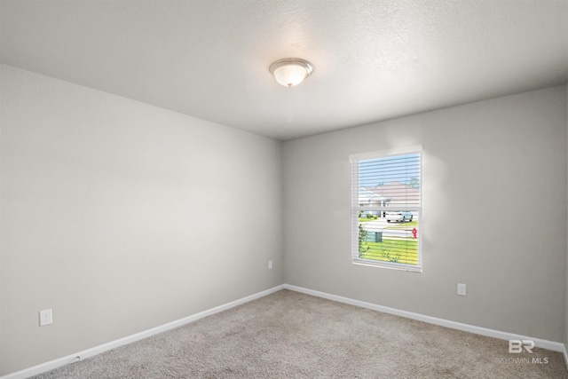 empty room featuring baseboards and carpet flooring