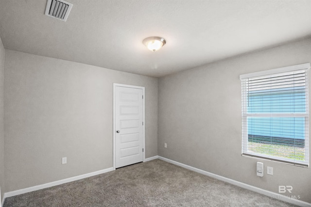 carpeted spare room featuring visible vents and baseboards