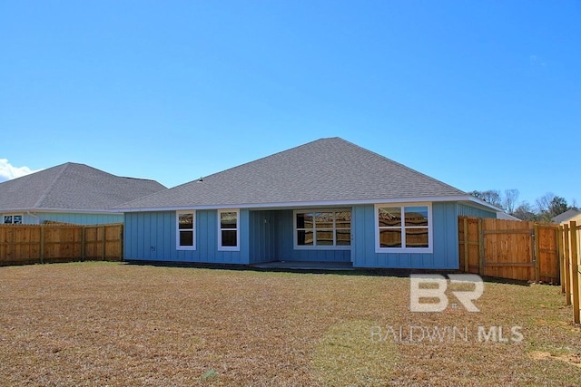 back of property featuring board and batten siding, a fenced backyard, roof with shingles, and a yard