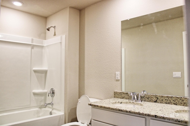 bathroom with a textured wall, vanity, shower / washtub combination, and toilet