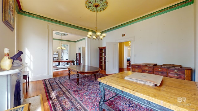 interior space featuring hardwood / wood-style floors, ornamental molding, and an inviting chandelier