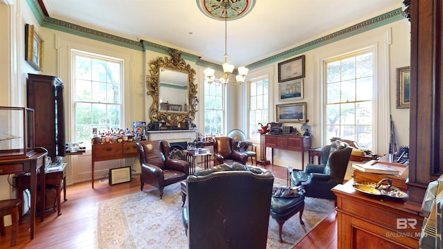 living room with ornamental molding, a healthy amount of sunlight, a notable chandelier, and hardwood / wood-style floors