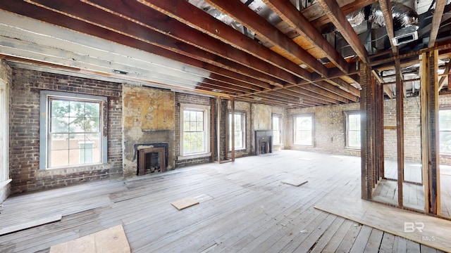 interior space with hardwood / wood-style floors, a large fireplace, brick wall, and a wealth of natural light