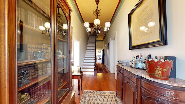 hall with ornamental molding, an inviting chandelier, and wood-type flooring