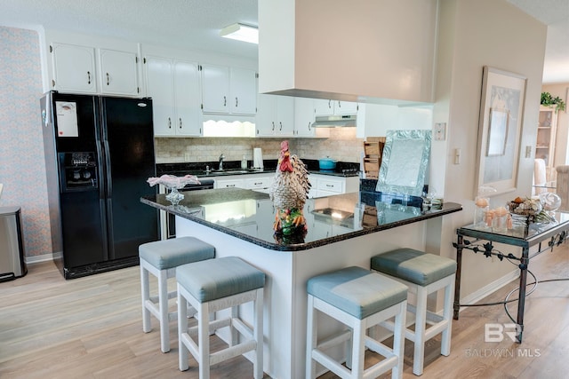 kitchen with kitchen peninsula, a kitchen breakfast bar, white cabinetry, black fridge with ice dispenser, and light hardwood / wood-style flooring