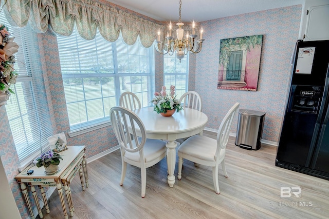 dining space with light hardwood / wood-style flooring and a chandelier