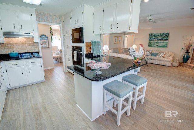 kitchen featuring white cabinetry, ceiling fan, black appliances, and a breakfast bar