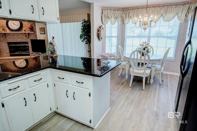 kitchen with kitchen peninsula, white cabinets, hanging light fixtures, and refrigerator