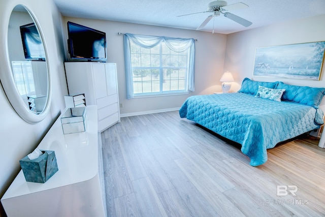 bedroom with ceiling fan, a textured ceiling, and light wood-type flooring