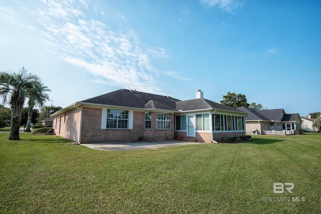 ranch-style house featuring a front yard, a patio, and a sunroom