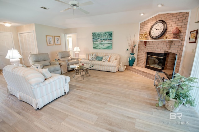 living room featuring light hardwood / wood-style floors, lofted ceiling, and a fireplace