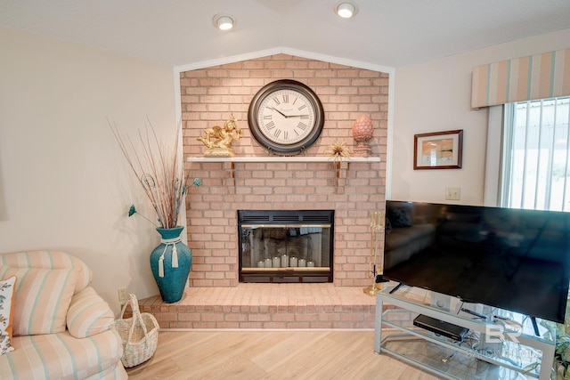 living room featuring lofted ceiling, wood-type flooring, and a fireplace