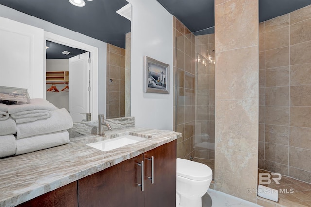 bathroom featuring toilet, vanity, and a tile shower